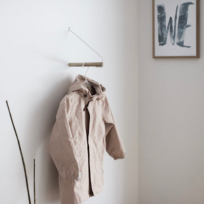 Garderobe "ADD MORE" aus hellbraunem Eichenholz und weißem Metallbügel in Szene mit beigem Mantel an Kleiderhaken