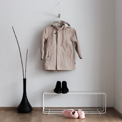 Garderobe "ADD MORE" aus hellbraunem Eichenholz und weißem Metallbügel an Wand mit beigem Mantel