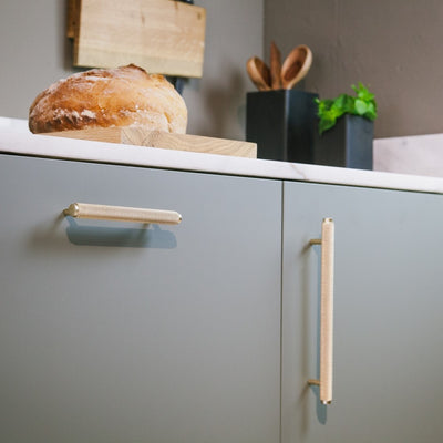 Messing Möbelgriffe in kurzer und langer Ausführung an grünen Küchenunterschrank angebracht.